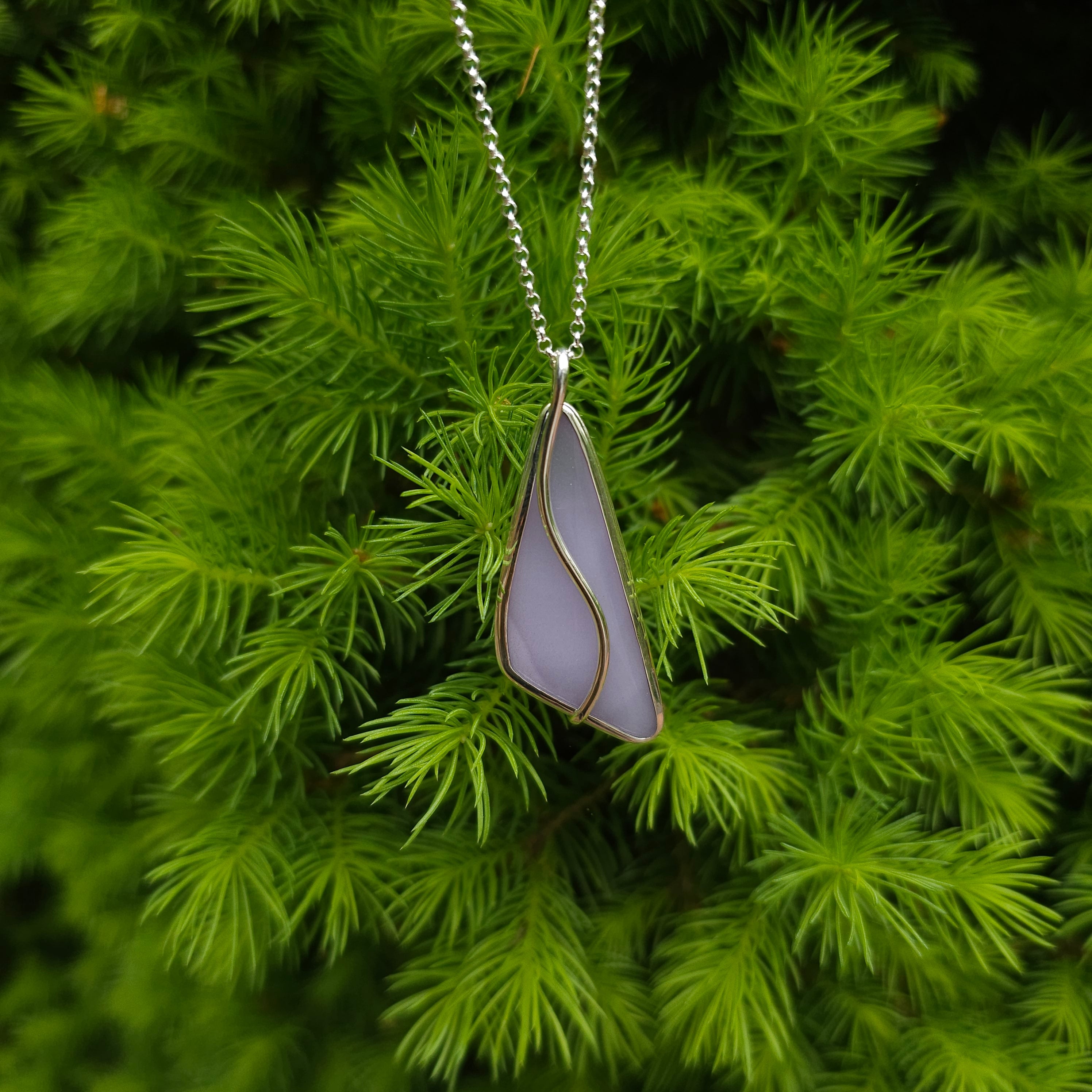 Cobalt blue glass teardrop with sterling silver spiral necklace shown on neck display.