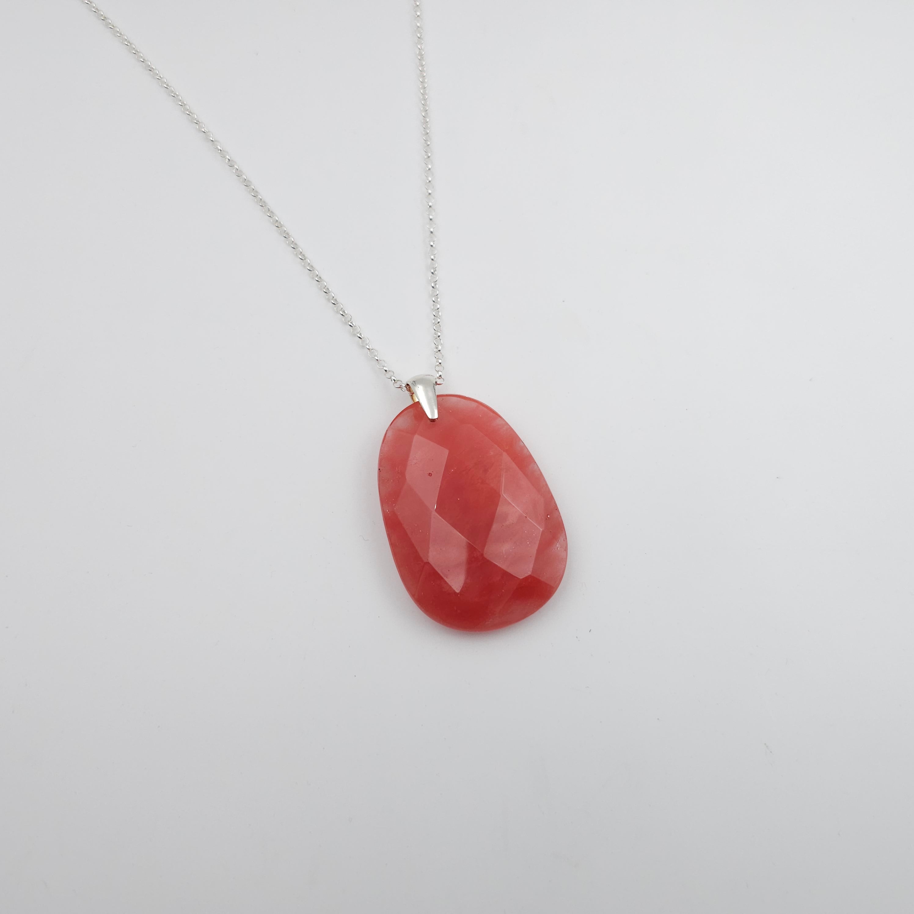 Large faceted light red oval/teardrop shaped bead with silver bail, on silver chain