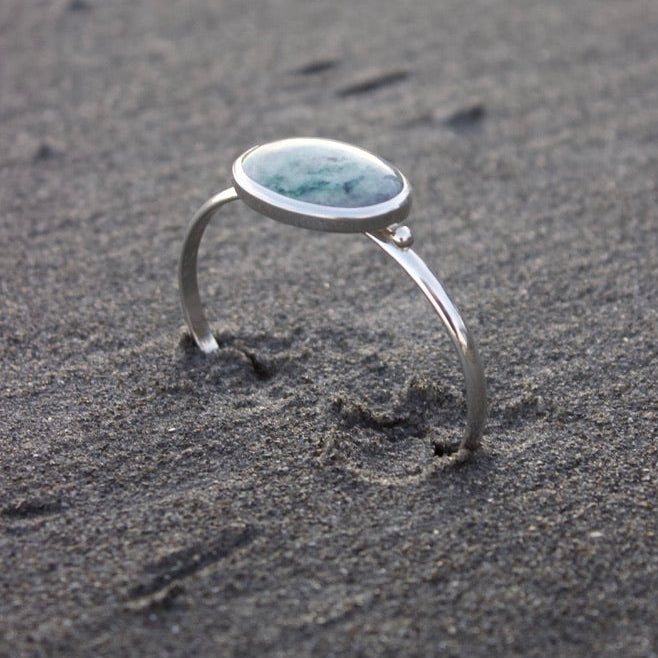 Silver cuff bracelet with bezel set light green stone