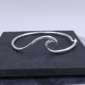 Polished sterling silver bracelet featuring a n ocean wave design