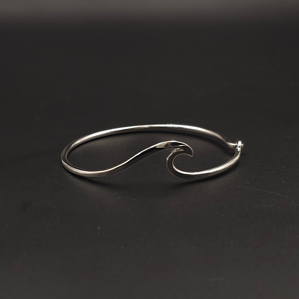 Silver wave-shaped bangle on a black background