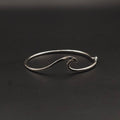 Silver wave-shaped bangle on a black background