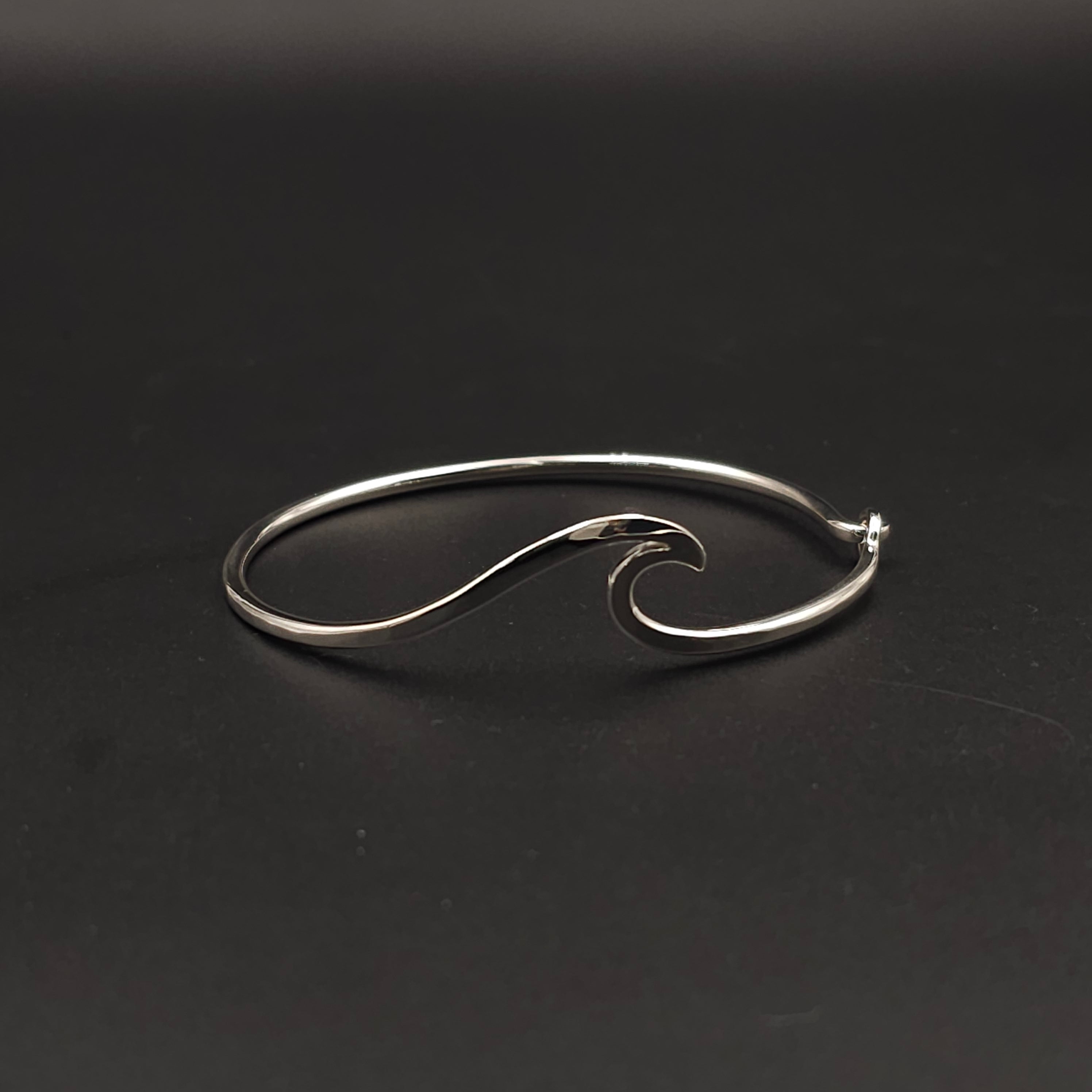 Silver wave-shaped bangle on a black background