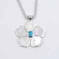 Silver flower-shaped pendant with a blue gemstone hanging on snake chain