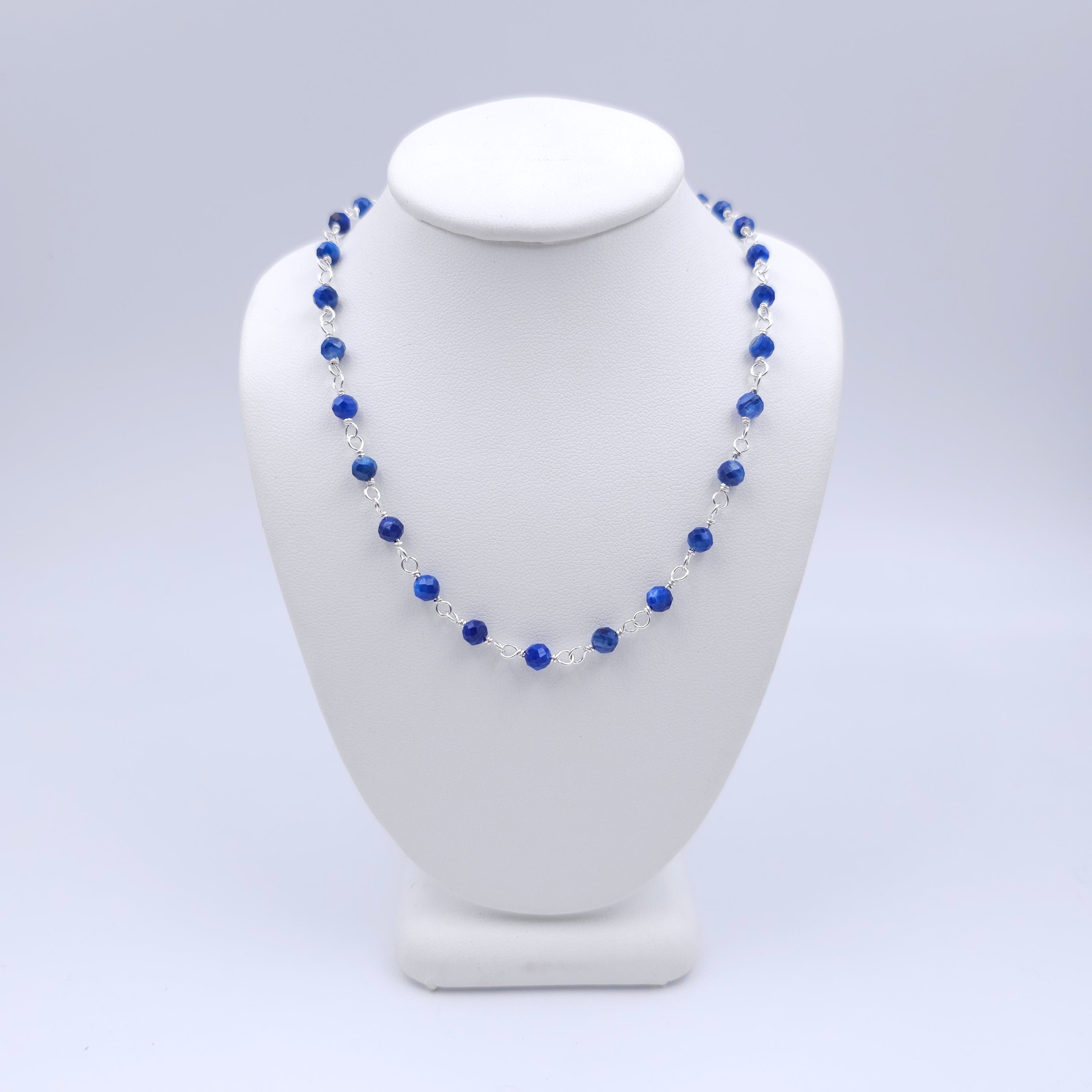 Blue faceted round beaded necklace with silver loops linking the beads together.
