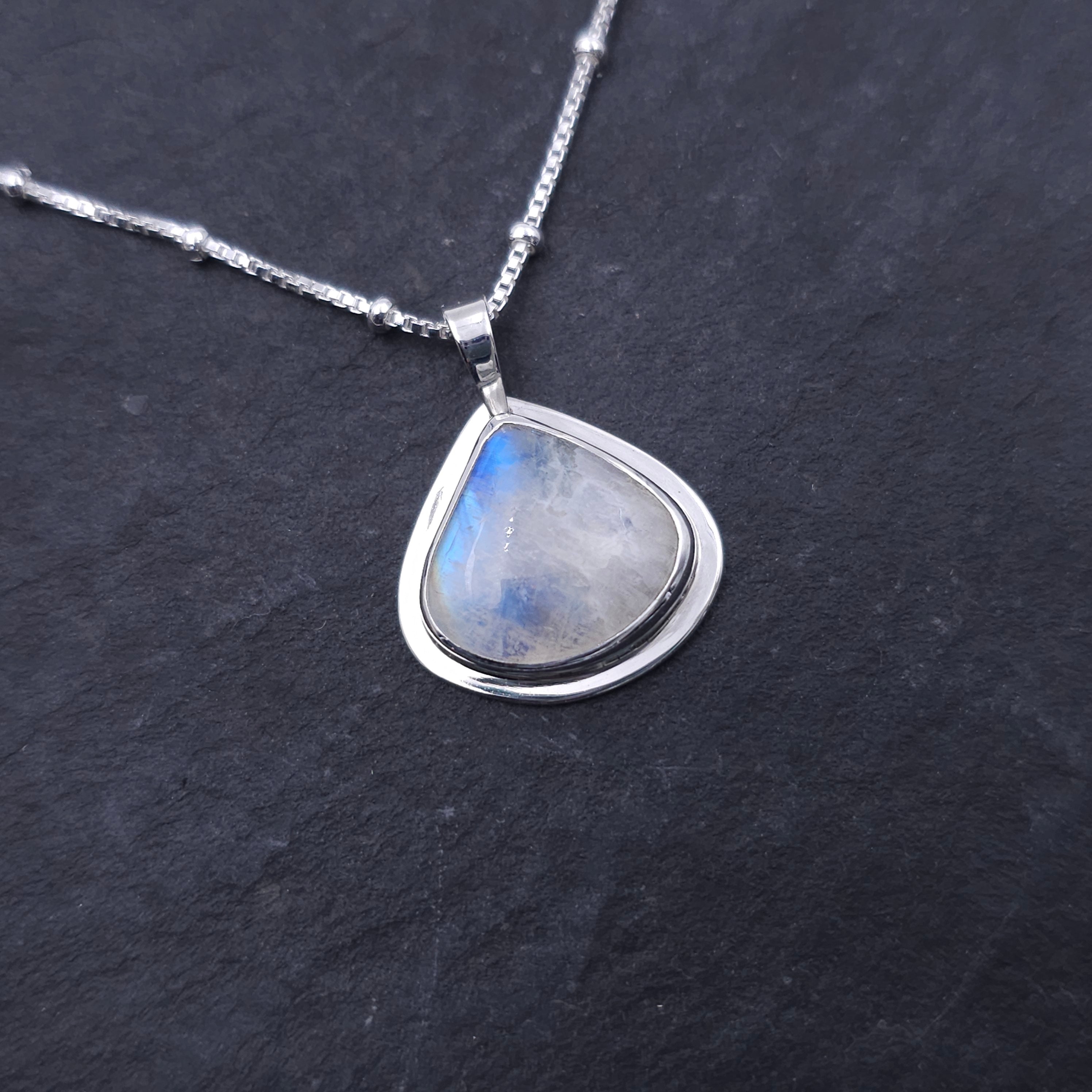 Silver necklace with a teardrop-shaped rainbow moonstone pendant