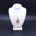 Oval bezel set peach moonstone necklace within an open silver wire frame