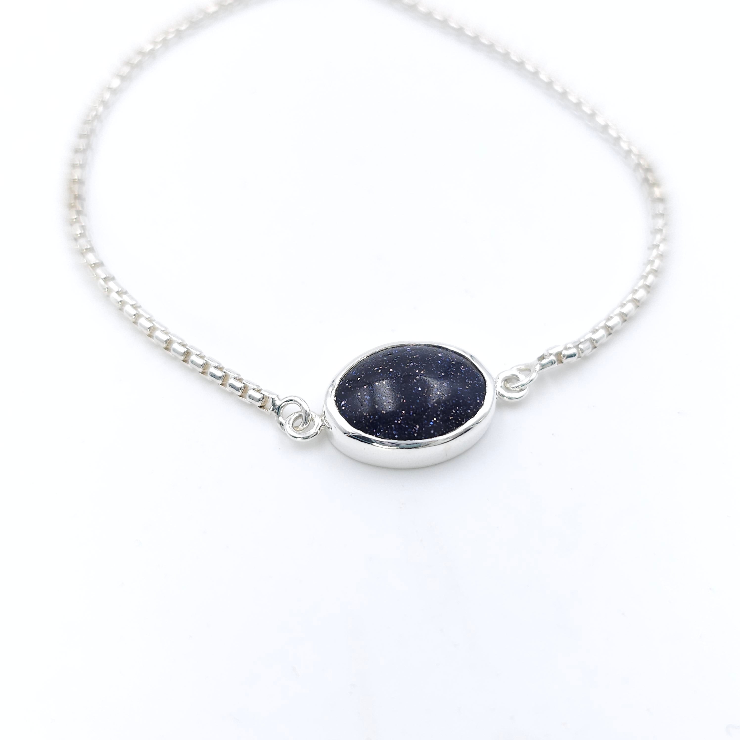 Adjustable silver chain bracelet with bezel set oval purple goldstone as centerpiece