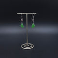 Green sea glass dangle earrings with tiny flower charms dangling between earring wires and green sea glass