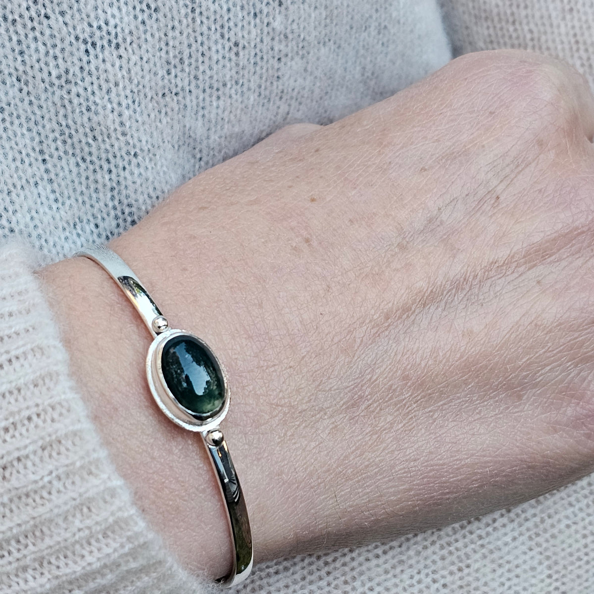 Oval bezel set moss agate with textured border sterling silver cuff bracelet