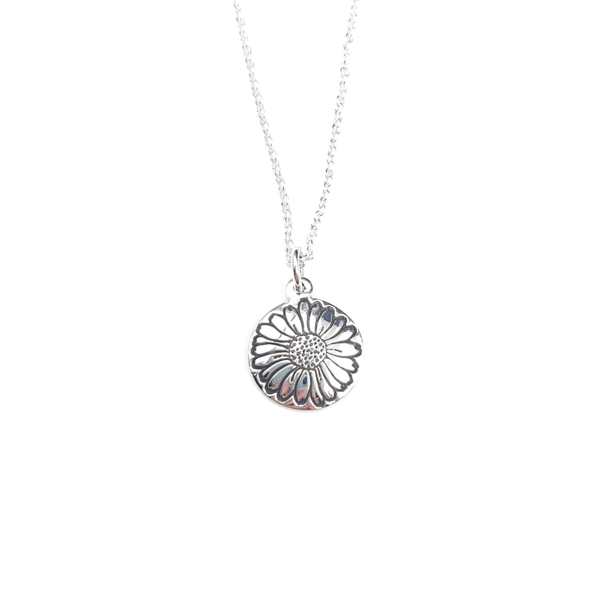 A silver stamped daisy round pendant necklace on a delicate silver chain