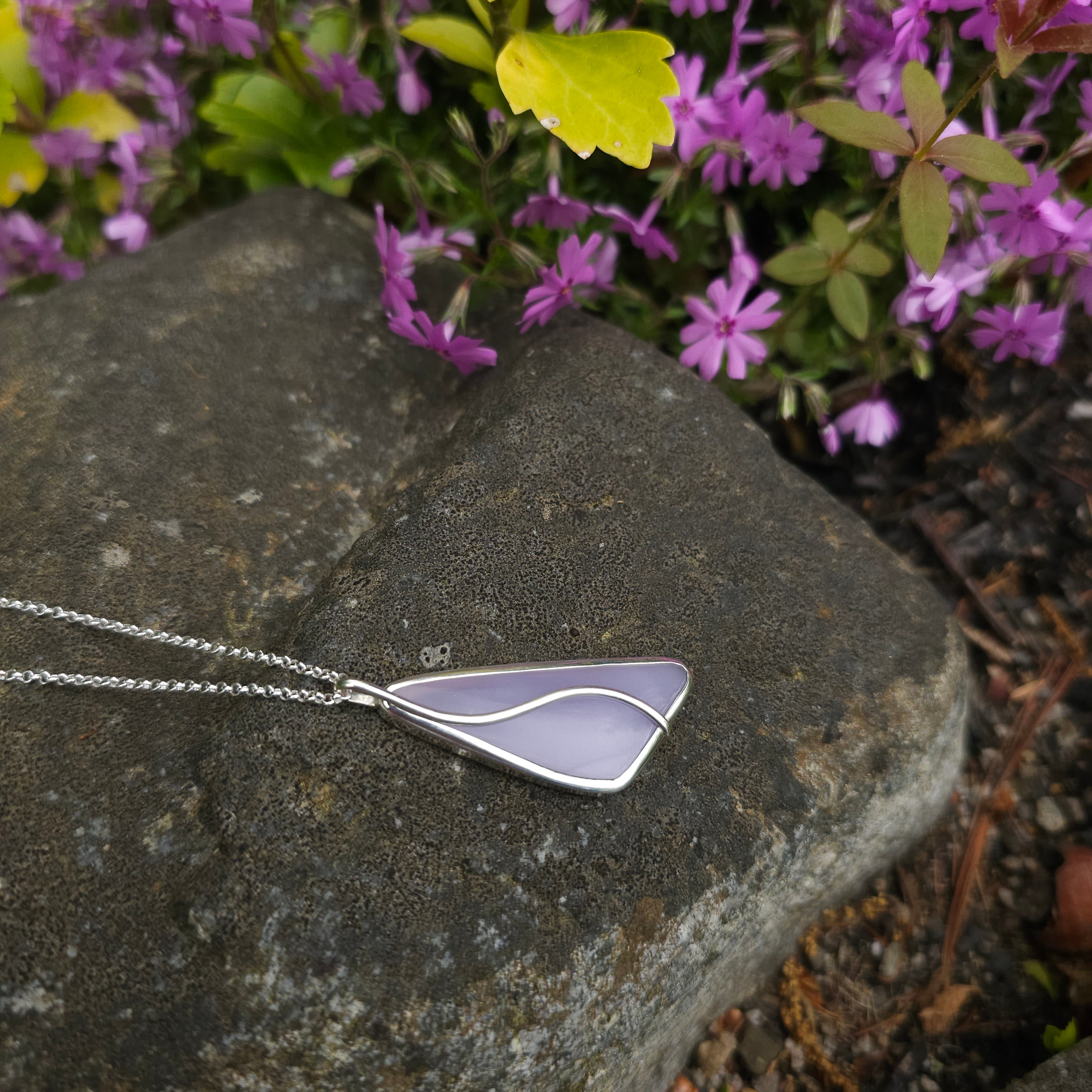 Light purple bezel set gemstone with curvy wire accent on top of pendant