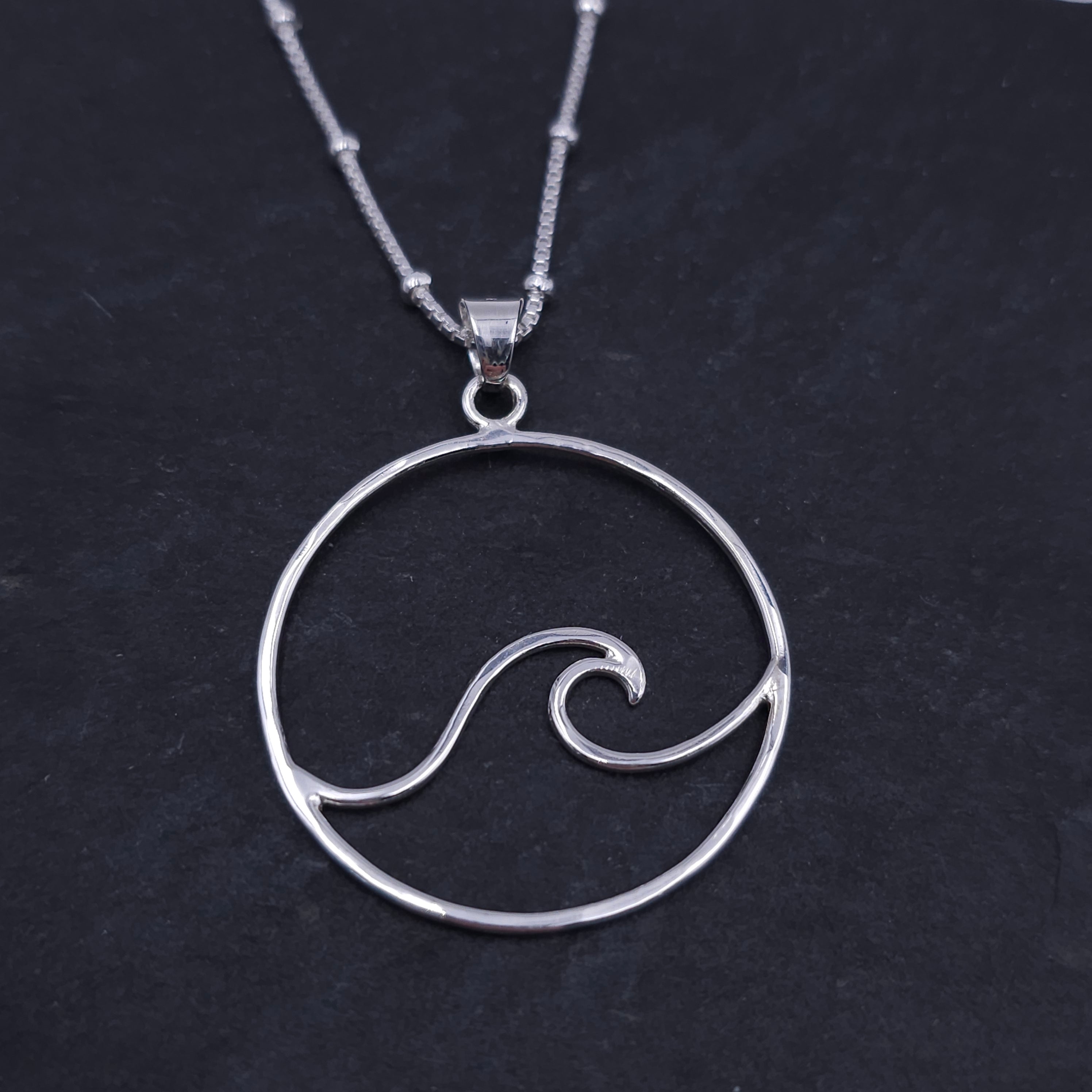 Open wire design with wave shape inside circle border. Silver bail attached to jump ring at top to provide movement.