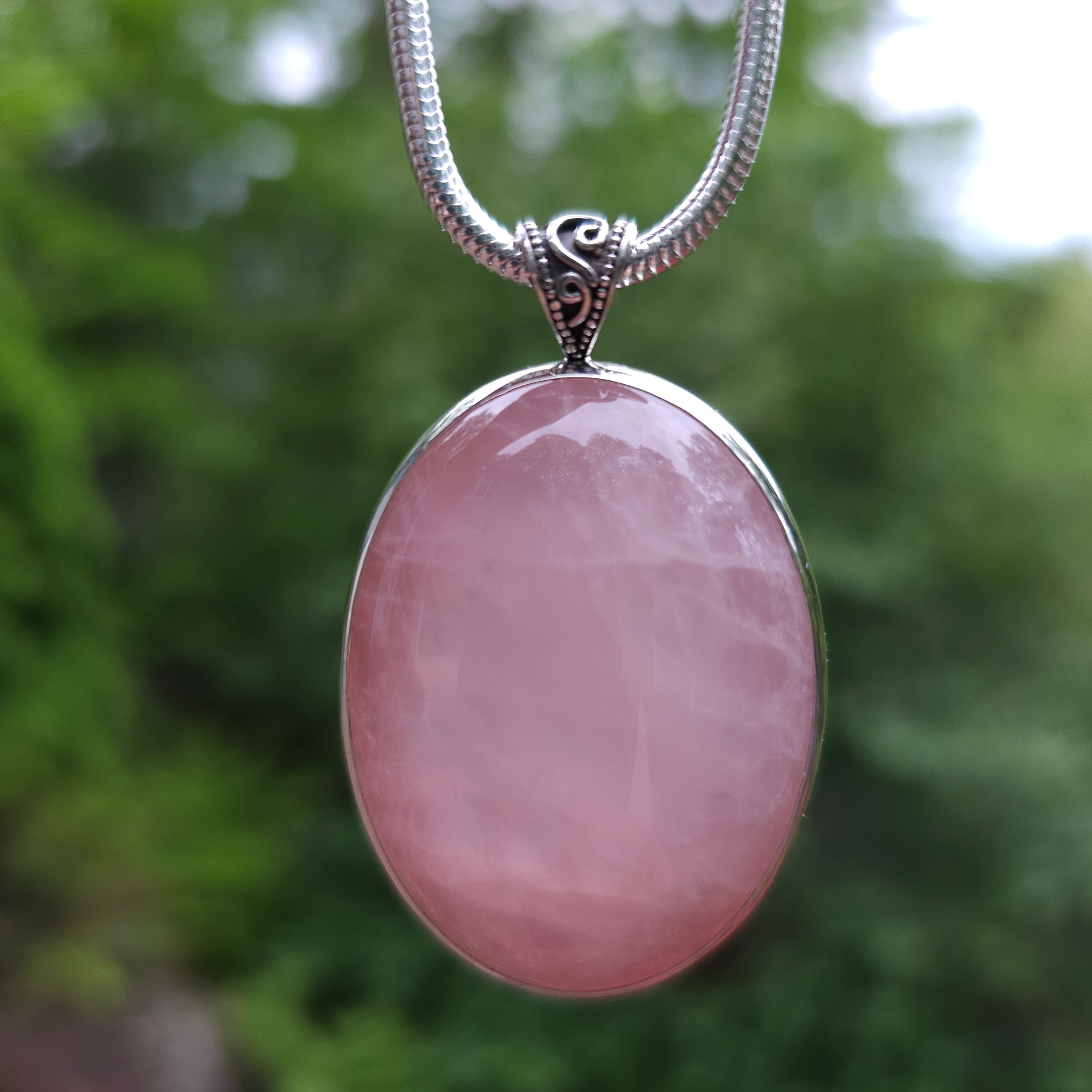 Large oval silver bezel necklace with a bail showing swirls of wire and a beaded border