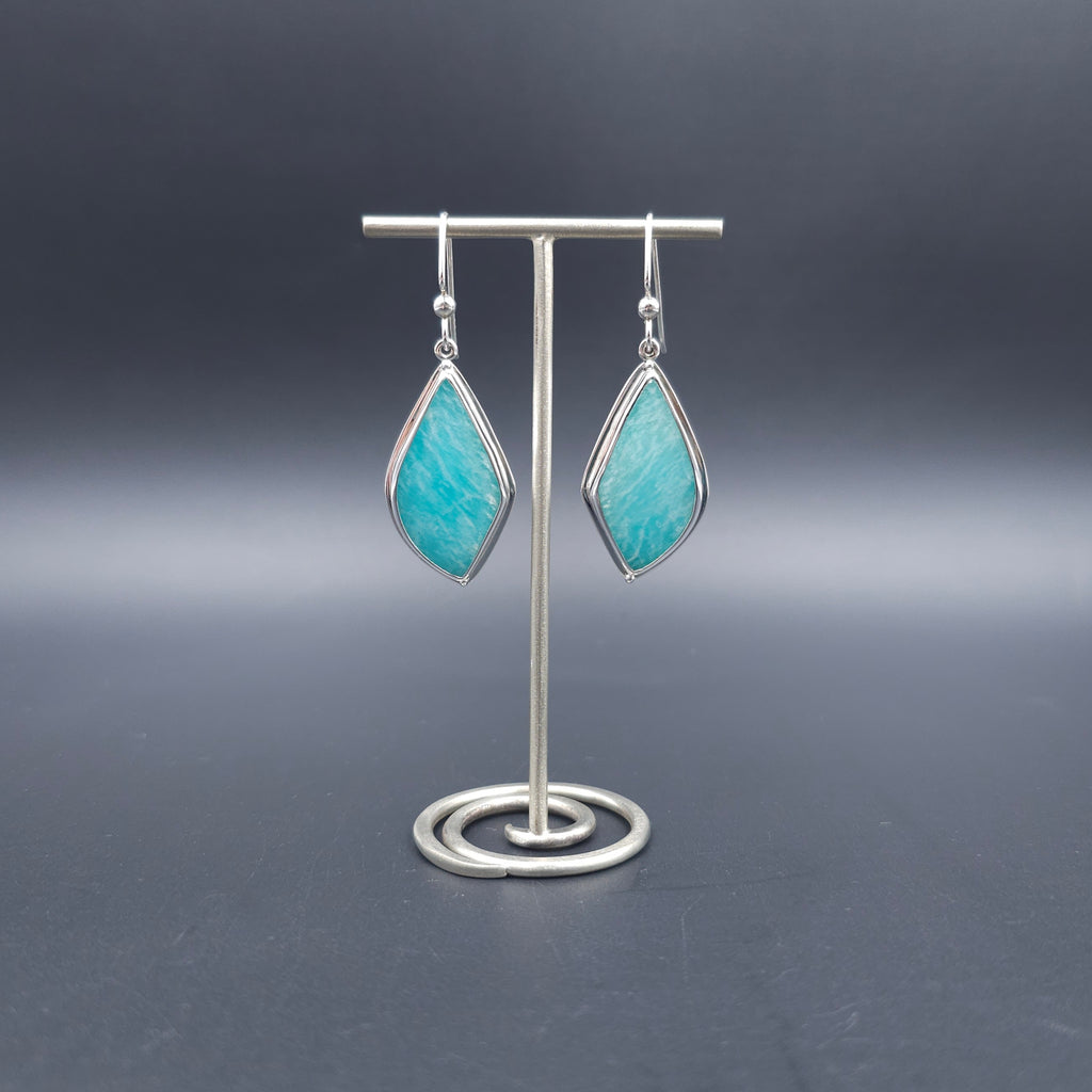 A pair of silver drop earrings with pointed teardrop-shaped turquoise-blue stone.