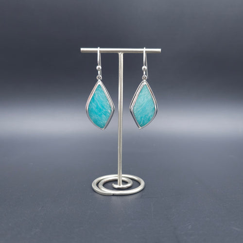 A pair of silver drop earrings with pointed teardrop-shaped turquoise-blue stone.