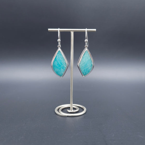 A pair of silver drop earrings with pointed teardrop-shaped turquoise-blue stone.
