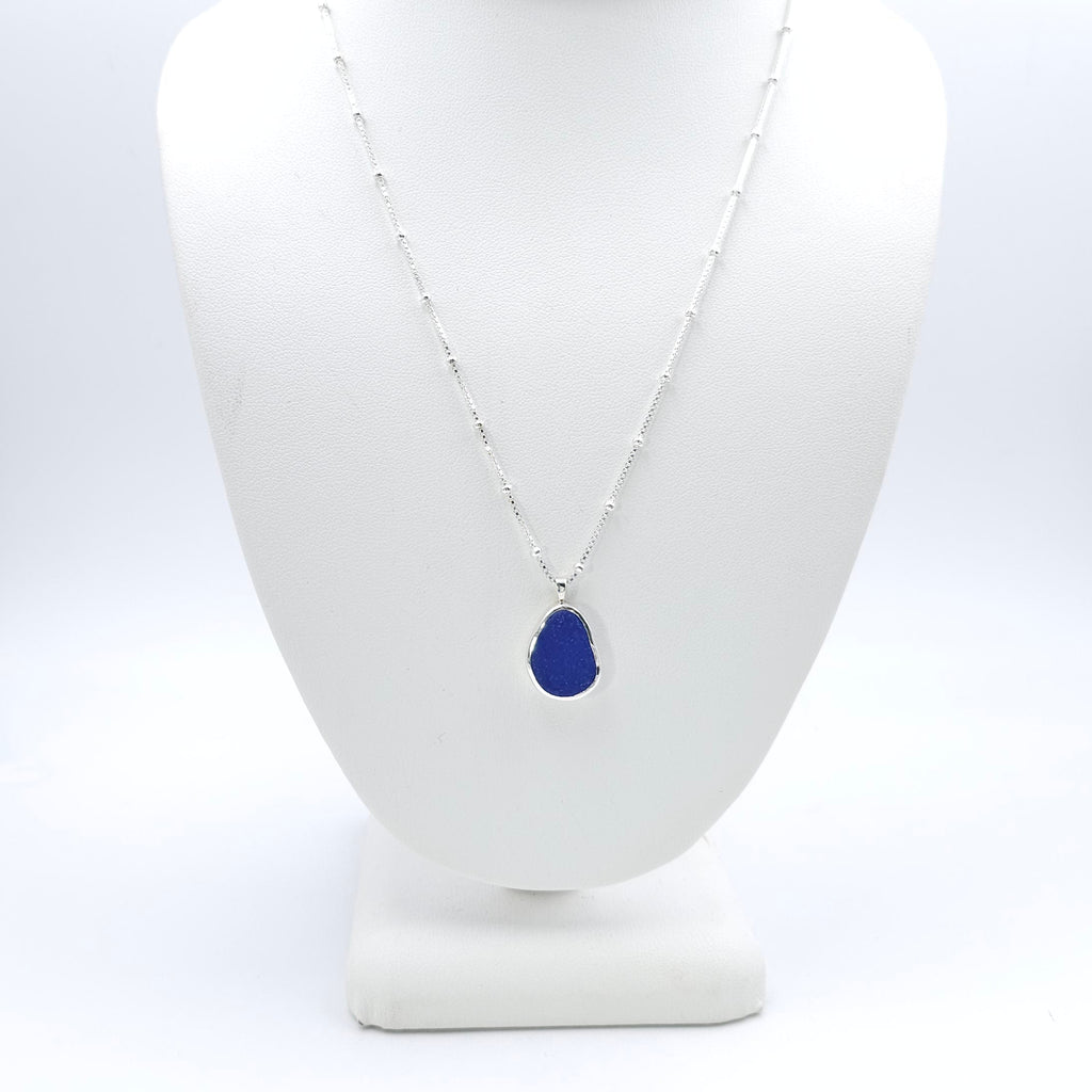 Oval shaped cobalt blue sea glass bezel set necklace on chain