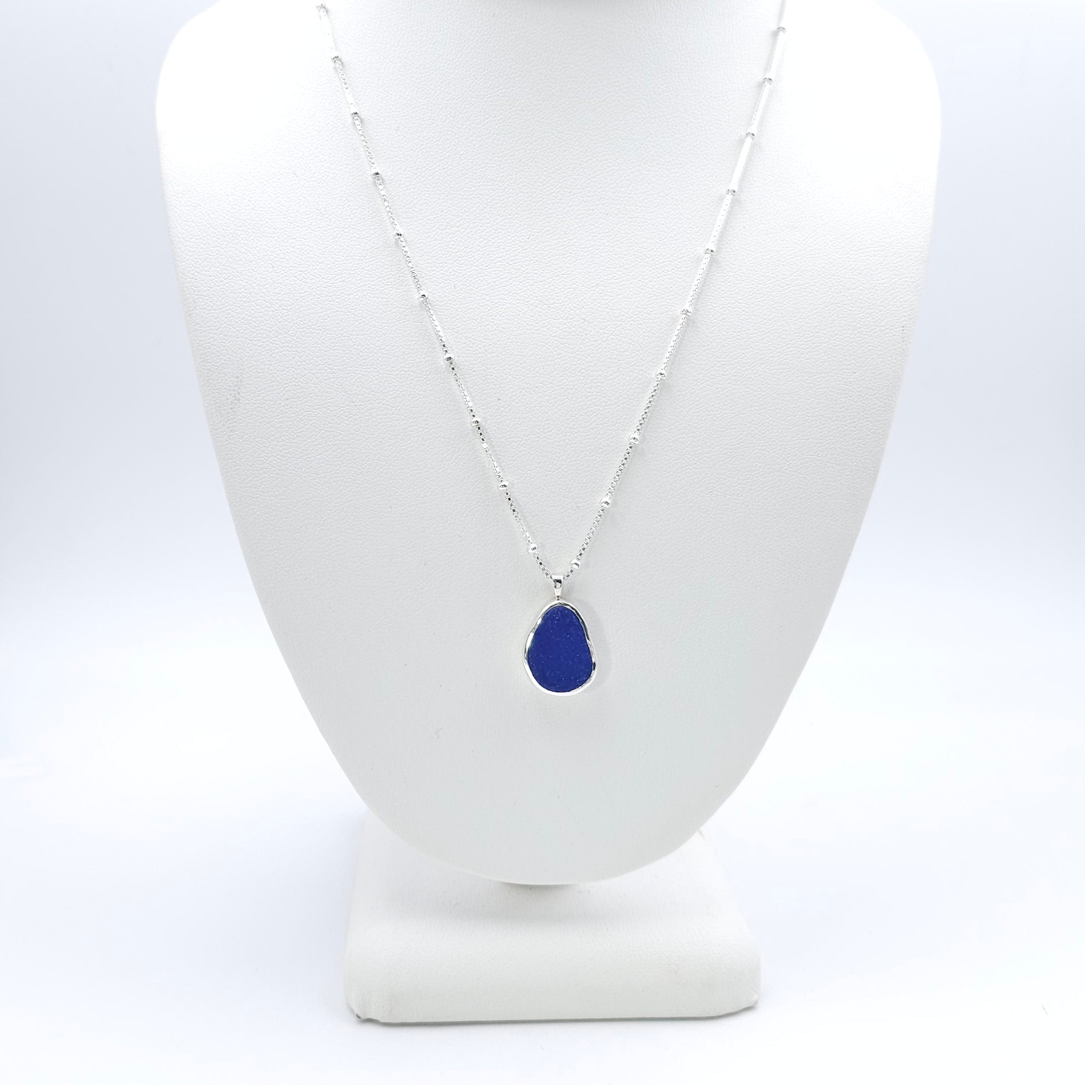 Oval shaped cobalt blue sea glass bezel set necklace on chain