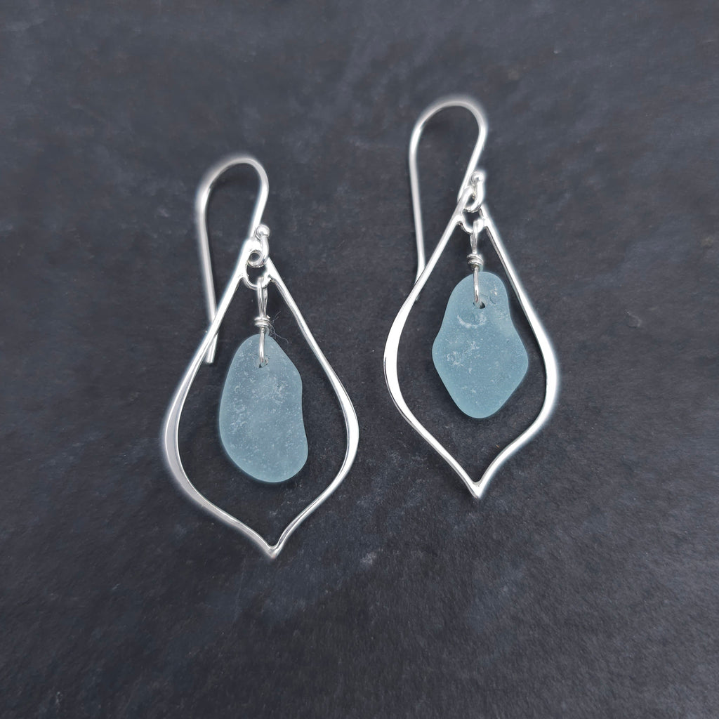 Silver wire in the shape of a pointed teardrop with light blue sea glass dangling inside the earrings.