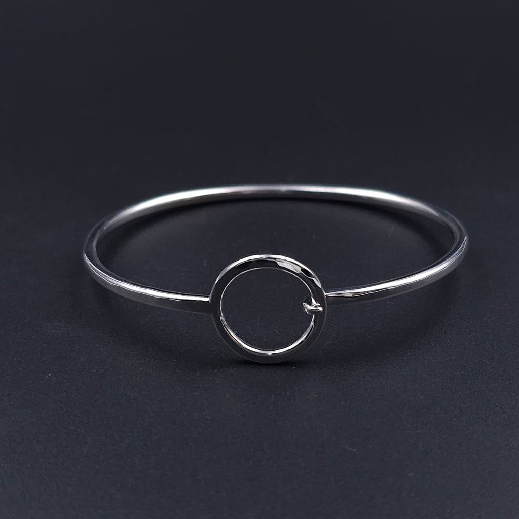 Silver wire bracelet, oval in shape, with open silver circle that is the centerpiece and also the loop to hook the other end onto 