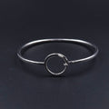 Silver wire bracelet, oval in shape, with open silver circle that is the centerpiece and also the loop to hook the other end onto 