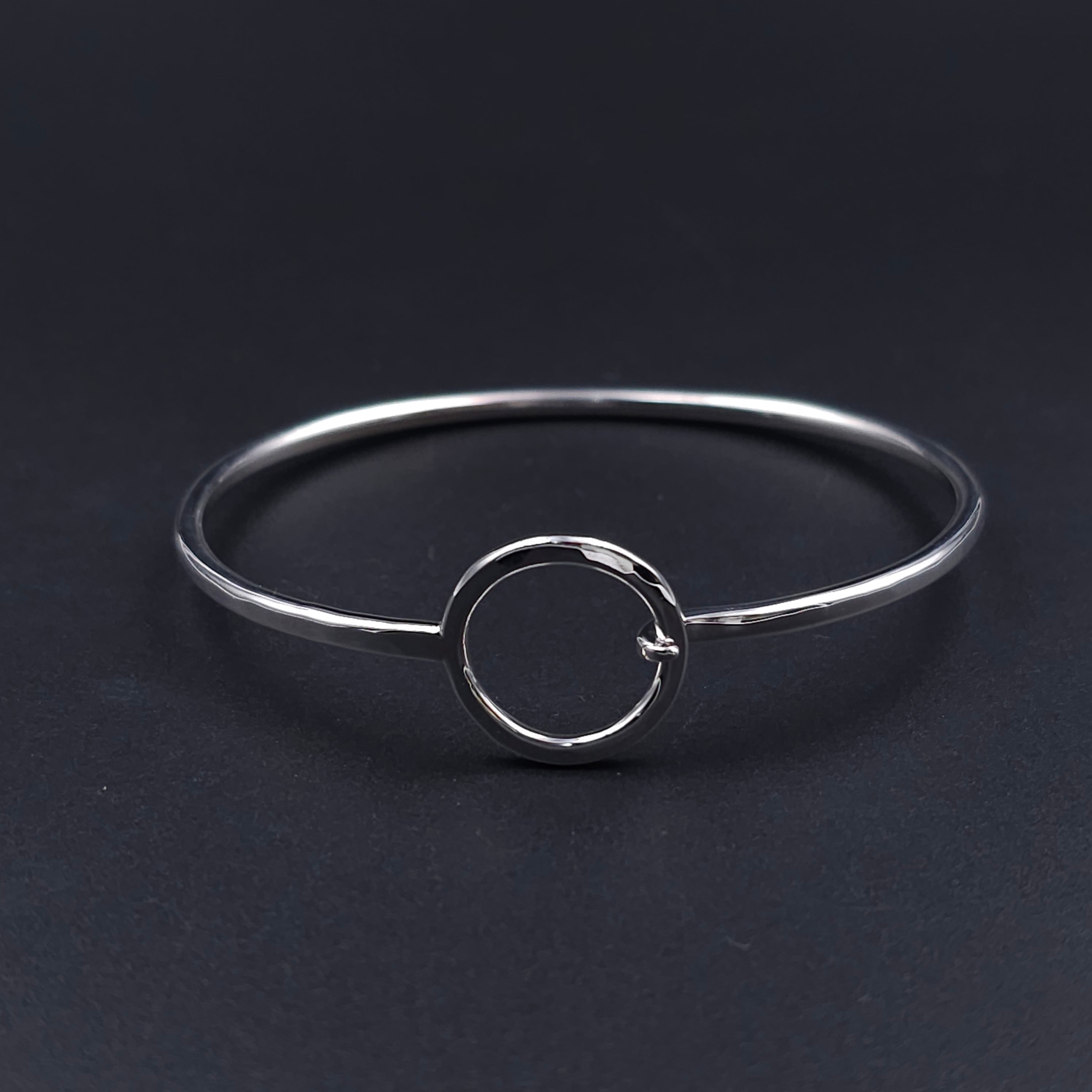 Silver wire bracelet, oval in shape, with open silver circle that is the centerpiece and also the loop to hook the other end onto 
