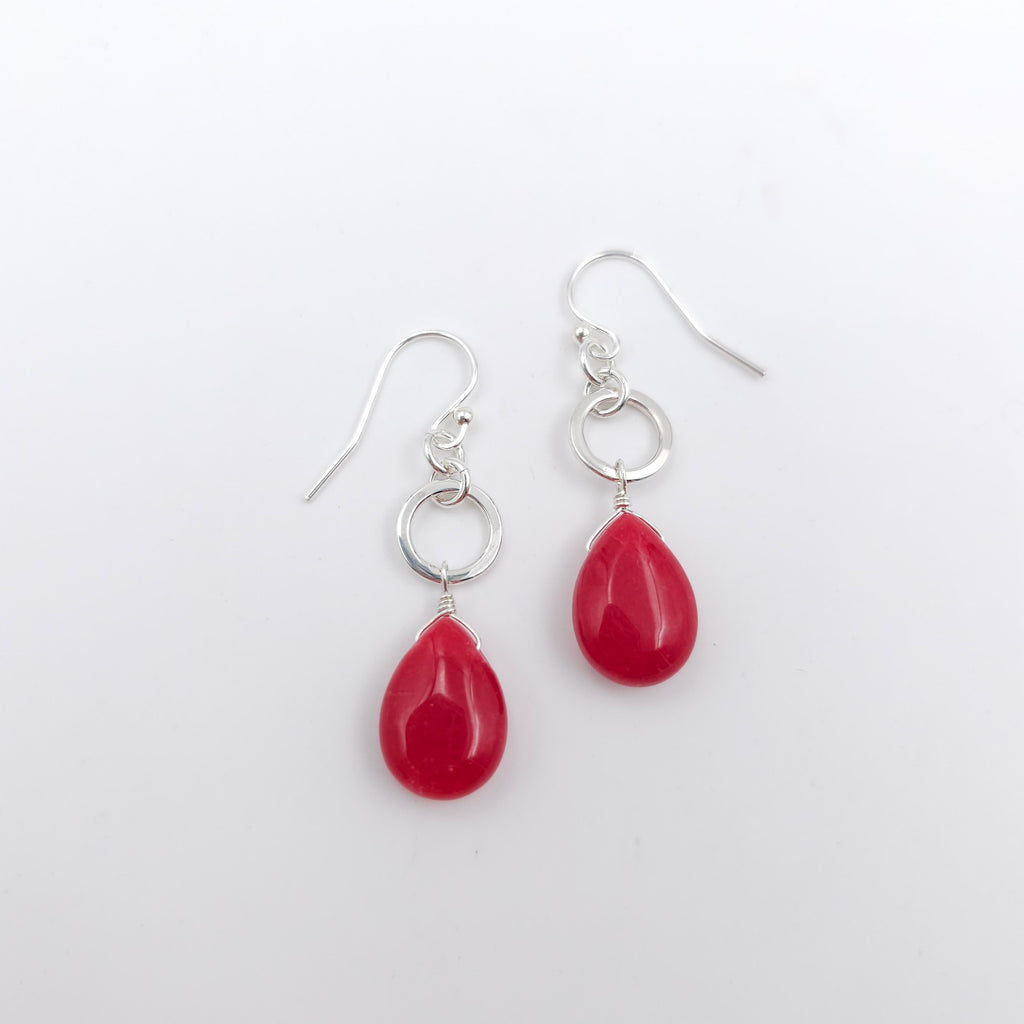 Red teardrop beads dangle from silver circles and hang from French earring wires