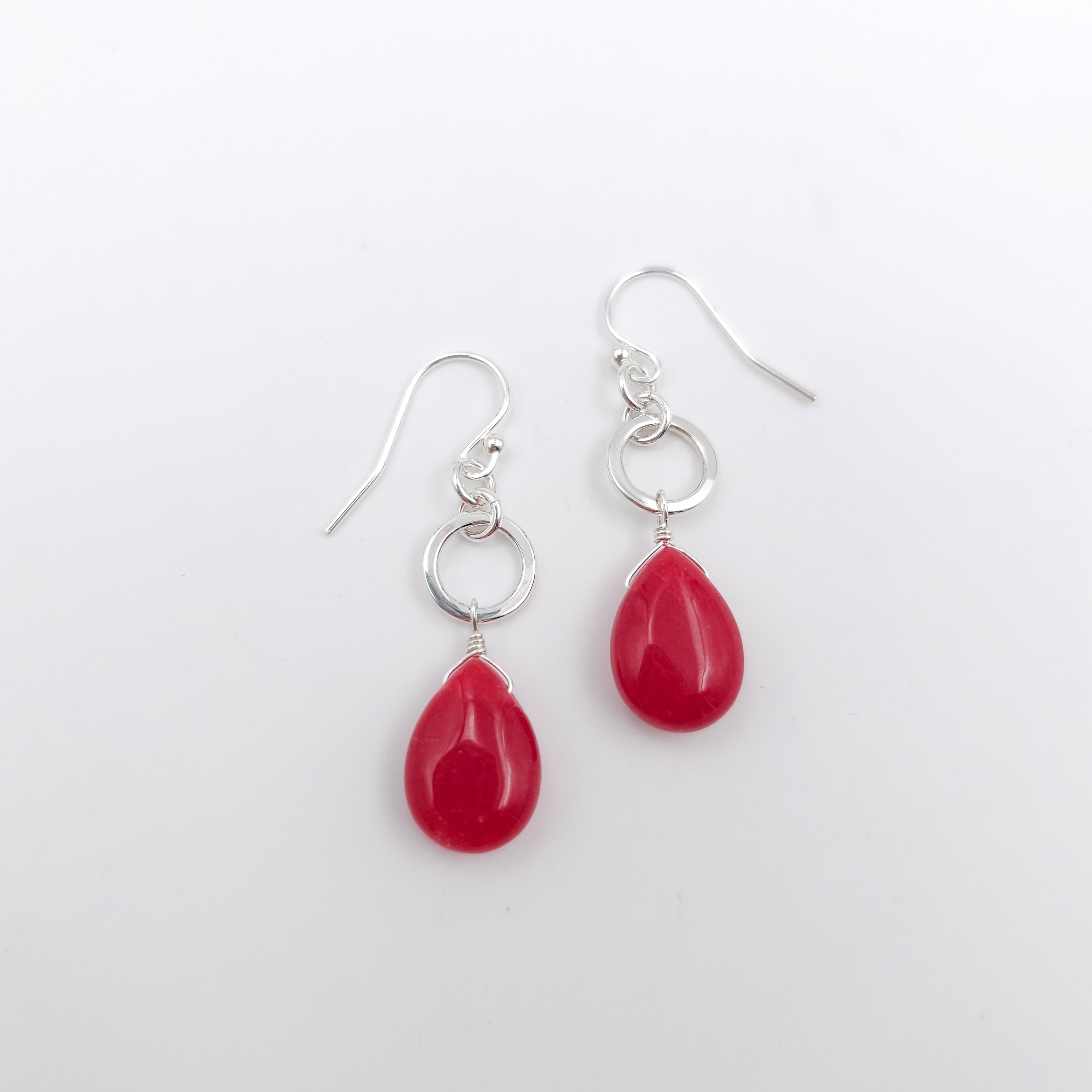 Red teardrop beads dangle from silver circles and hang from French earring wires