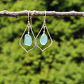 silver wire pointed teardrop dangle earrings with light blue sea glass dangling inside teardrop