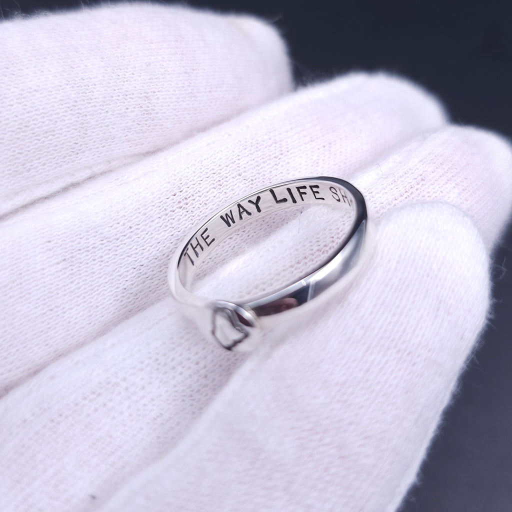 The inside of a silver ring that is stamped 'the way life should be'