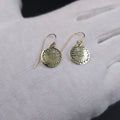 Round disc brass earrings with a daisy stamped in center of disc, hanging from french earrings wires