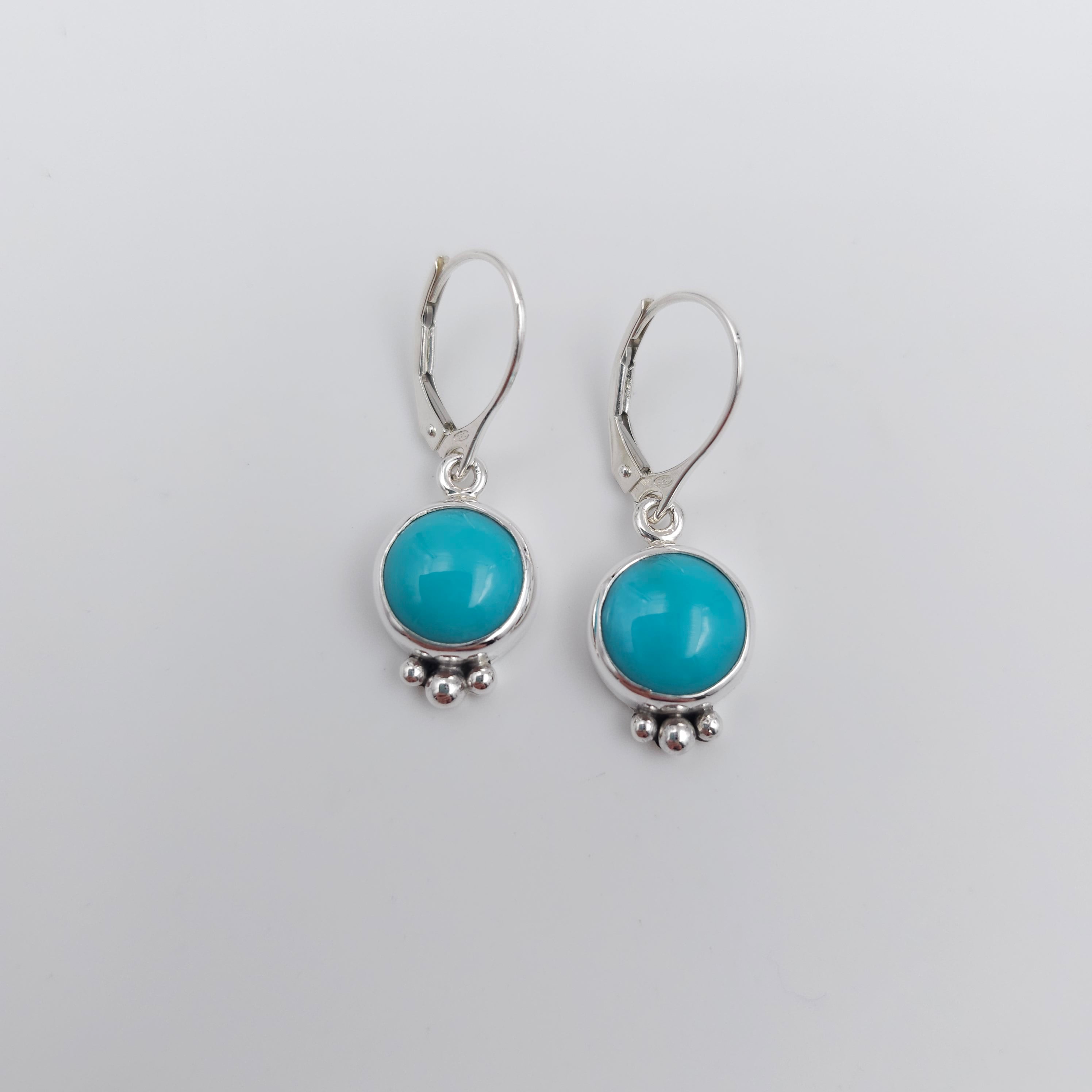 Round light blue turquoise silver earrings with three silver balls at bottom of bezel, hanging 