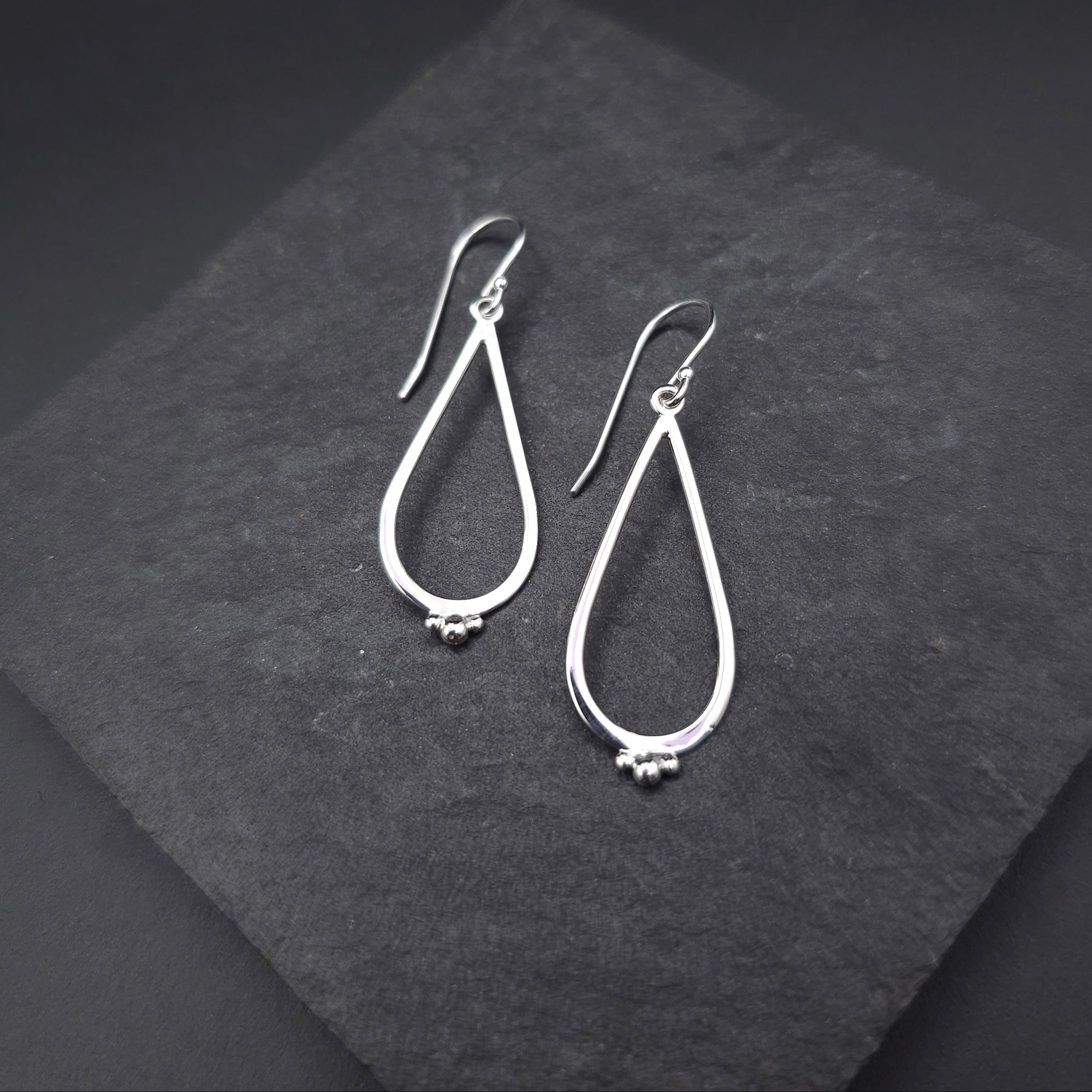 Silver teardrop open dangle earrings with three silver balls at bottom of teardrops