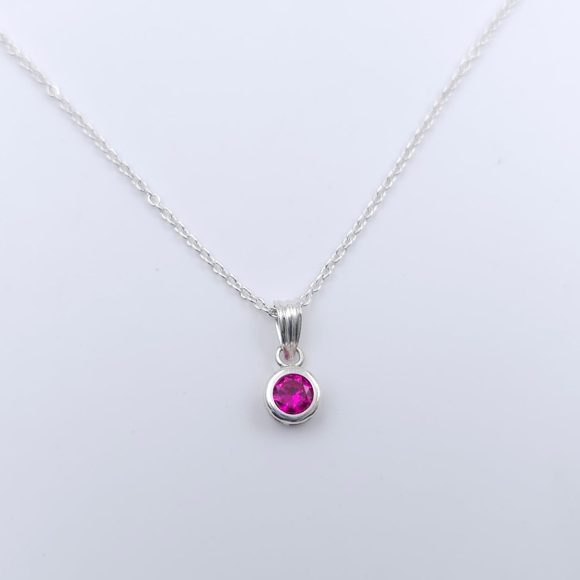 Round faceted dark pink bezel set silver pendant