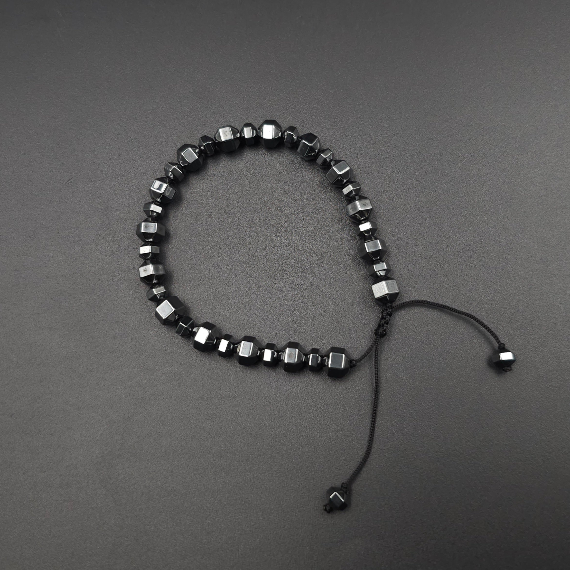 metallic gray hematite beads faceted in octagonal shape, strung on black cord adjustable bracelet