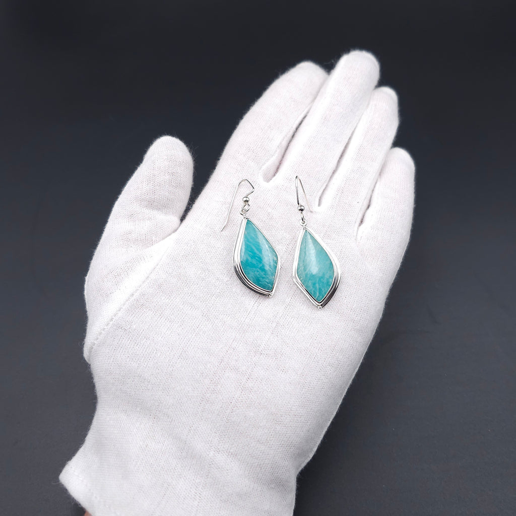 A pair of silver dangle earrings with pointed teardrop-shaped turquoise-blue stones