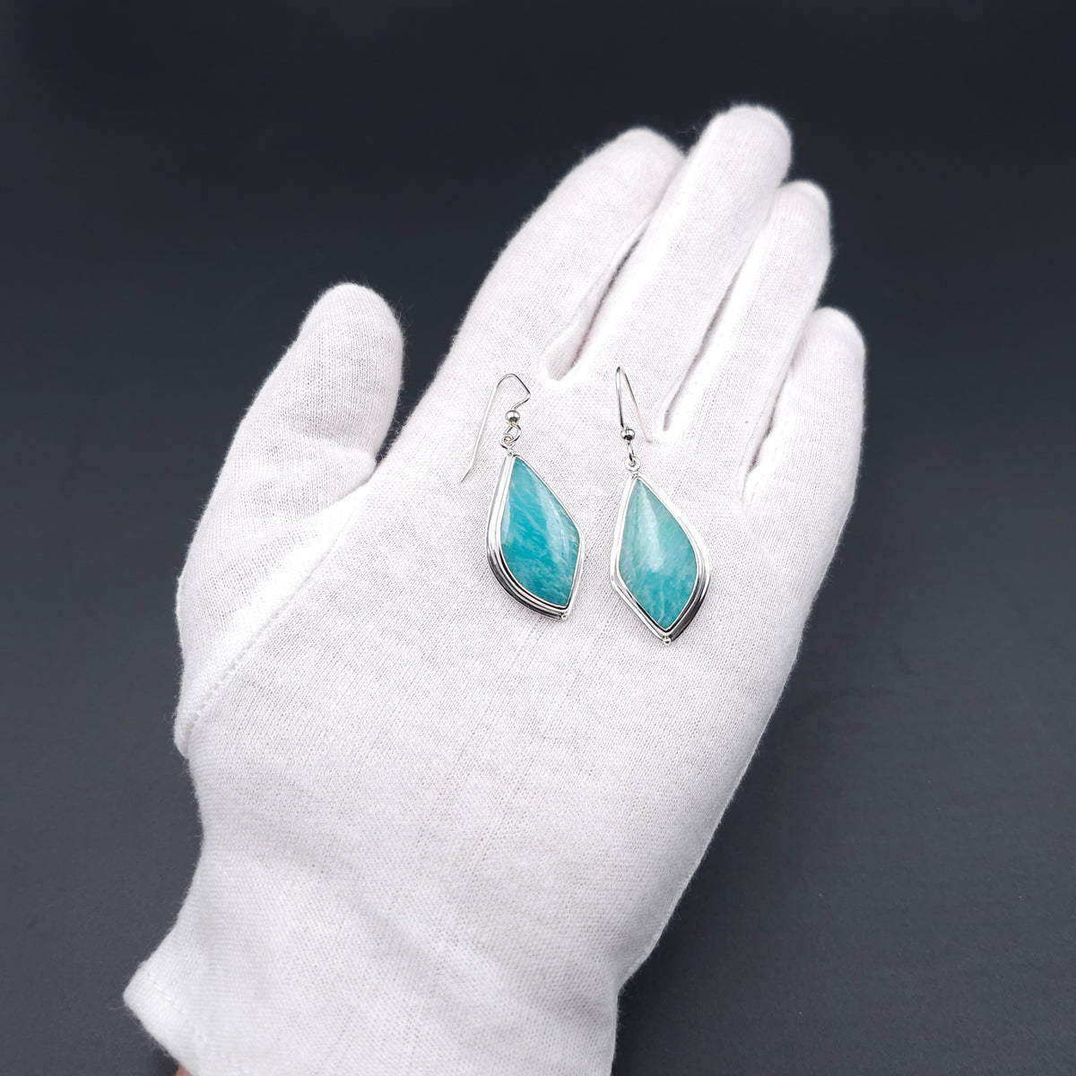 A pair of silver dangle earrings with pointed teardrop-shaped turquoise-blue stones
