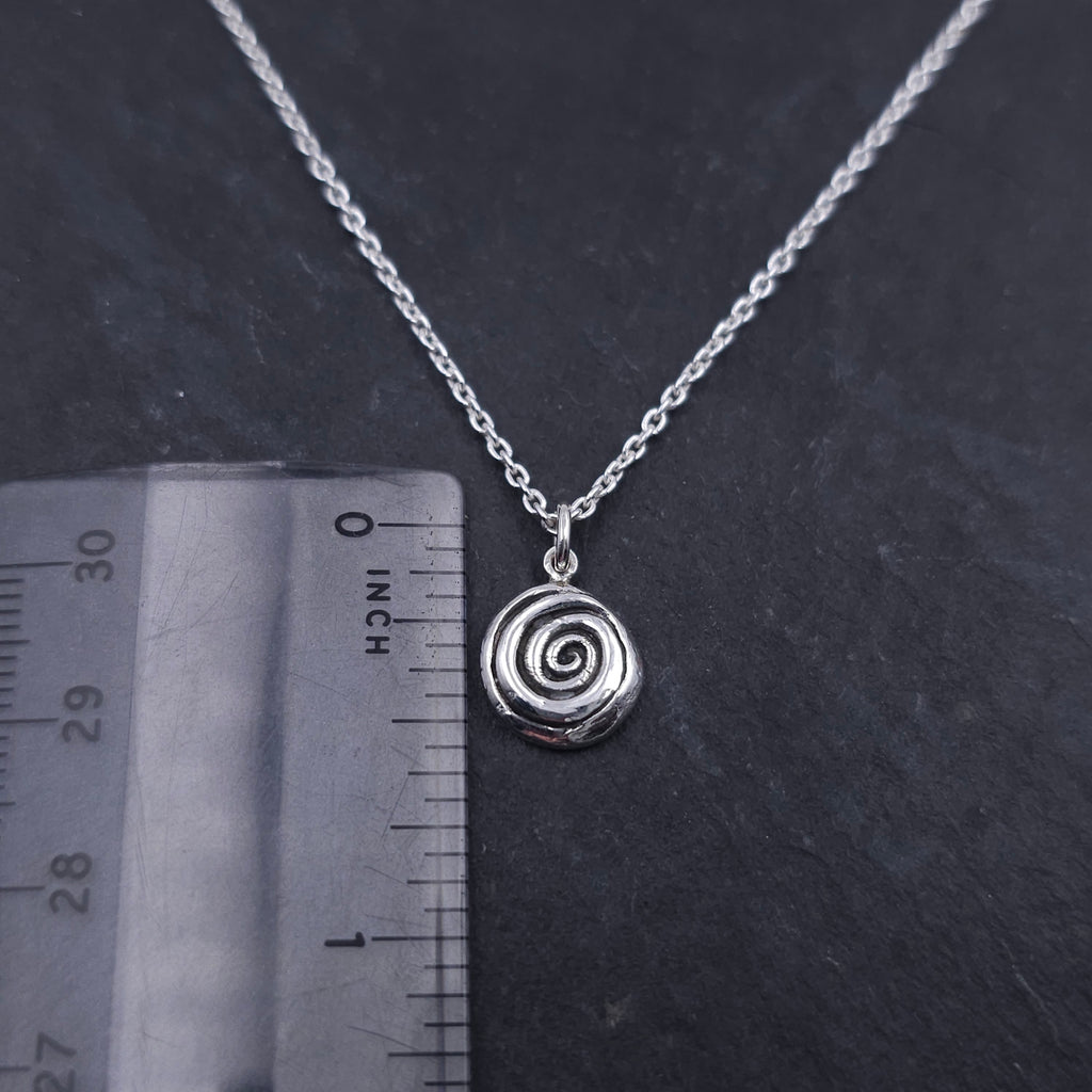 Silver spiral necklace next to ruler showing a little over 1/2" in length
