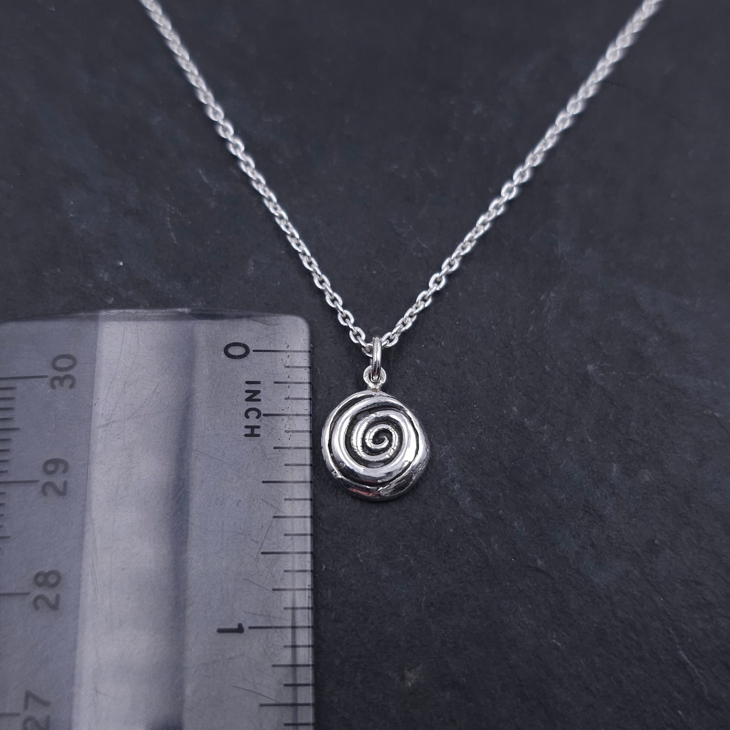 Silver spiral necklace next to ruler showing a little over 1/2" in length