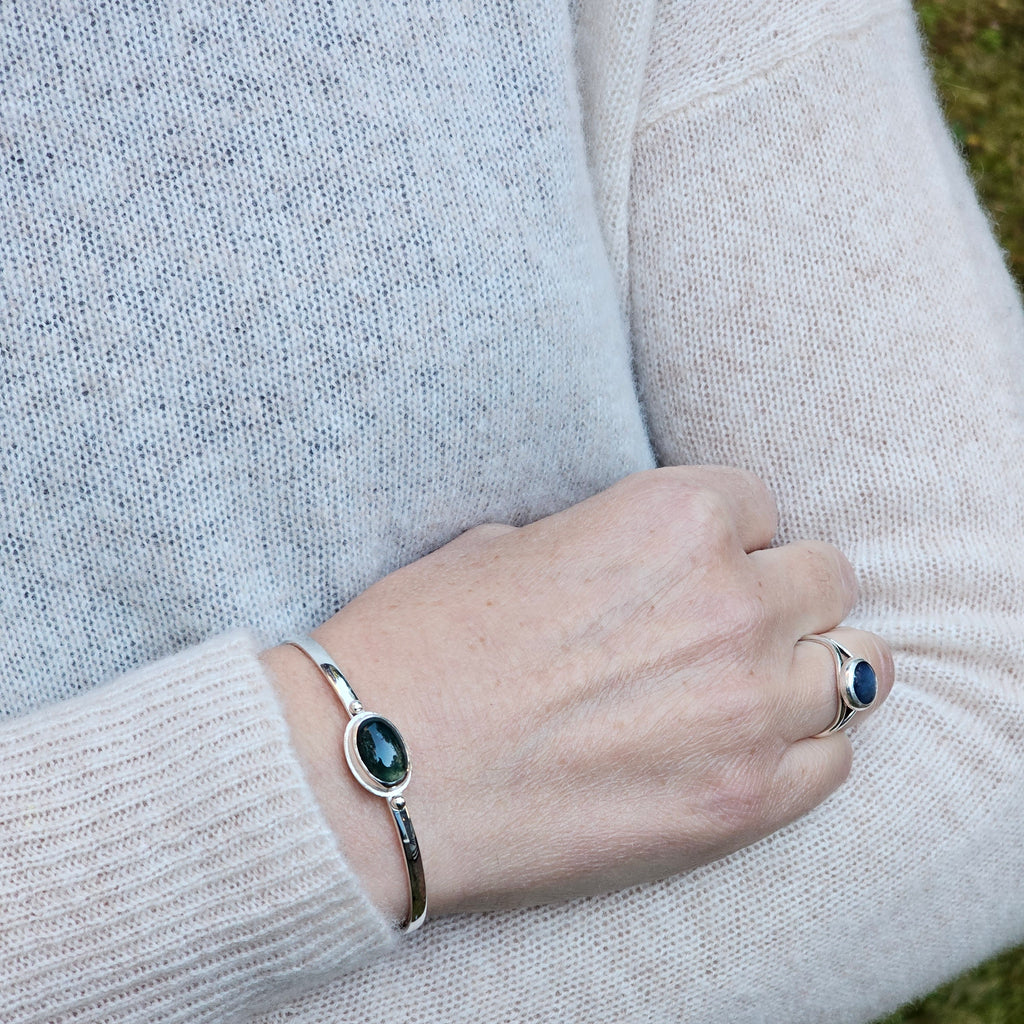 Oval bezel set moss agate with textured border sterling silver cuff bracelet