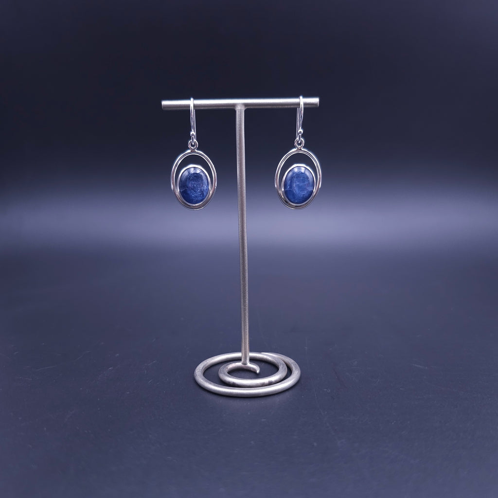A pair of silver dangle earrings with oval blue kyanite gemstones