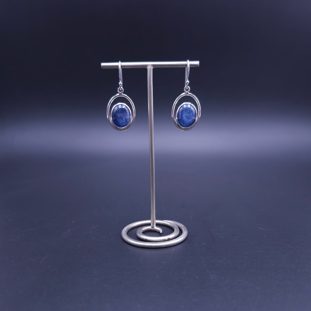 A pair of silver dangle earrings with oval blue kyanite gemstones