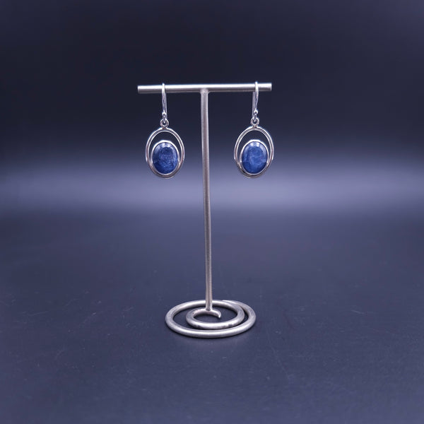 A pair of silver dangle earrings with oval blue kyanite gemstones