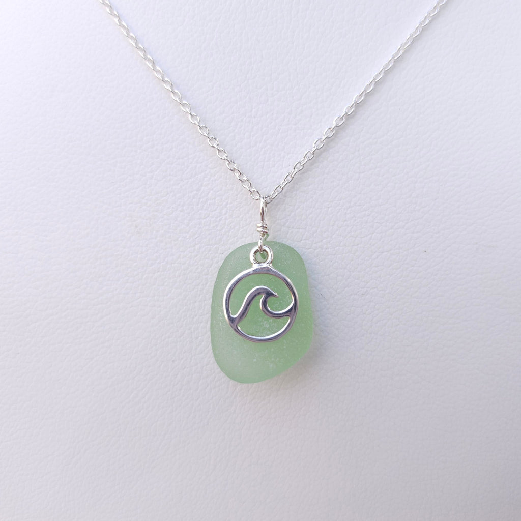 Light green sea glass necklace with silver wave in circle charm on top of sea glass