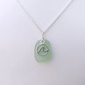 Light green sea glass necklace with silver wave in circle charm on top of sea glass