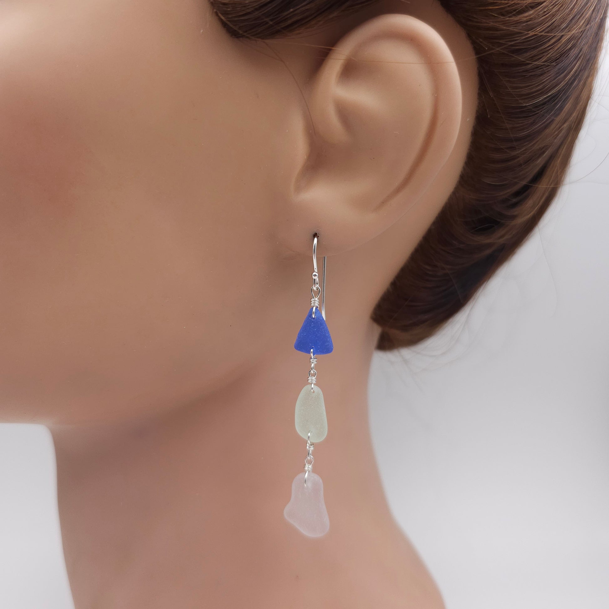 Triple sea glass earrings shown on mannequin: dark blue, light blue, and light purple sea glass.