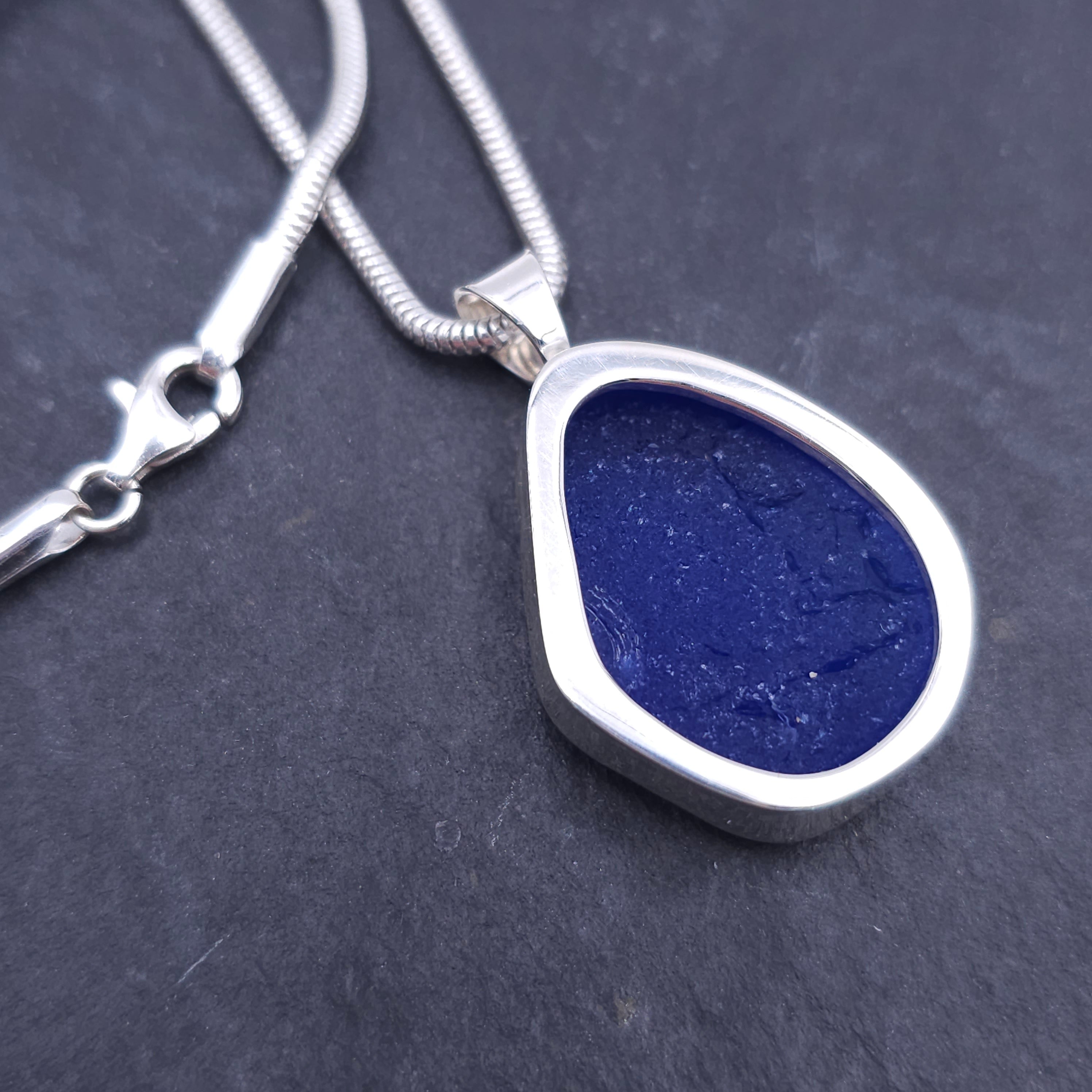 back side of blue sea glass necklace showing cut out back, with back of sea glass showing through.