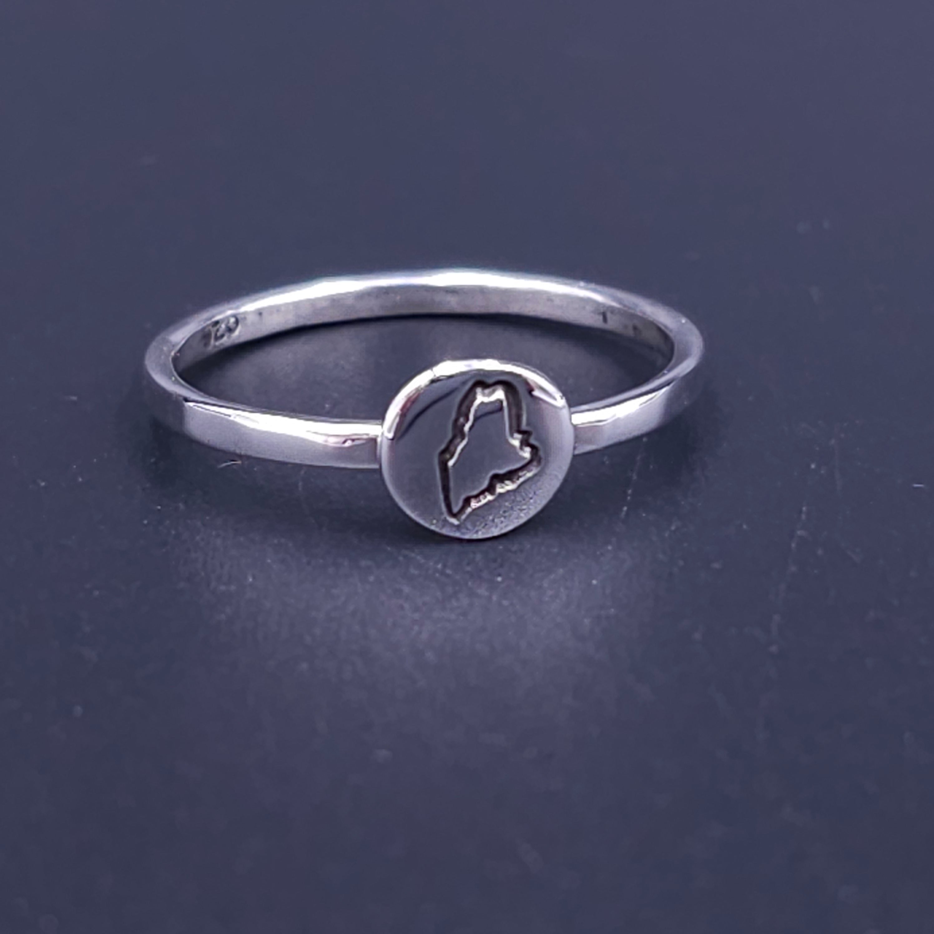 Silver ring with circle on top with the outline of the state of Maine