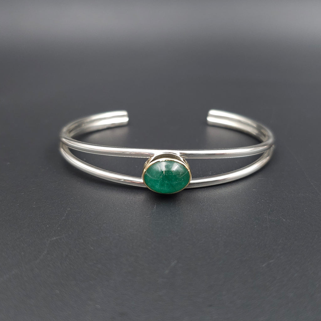 Double wire open cuff silver bracelet with gold bezel set emerald oval cabachon.